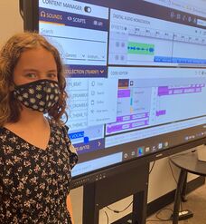 Student stands in front of her Python-coded Earsketch music composition